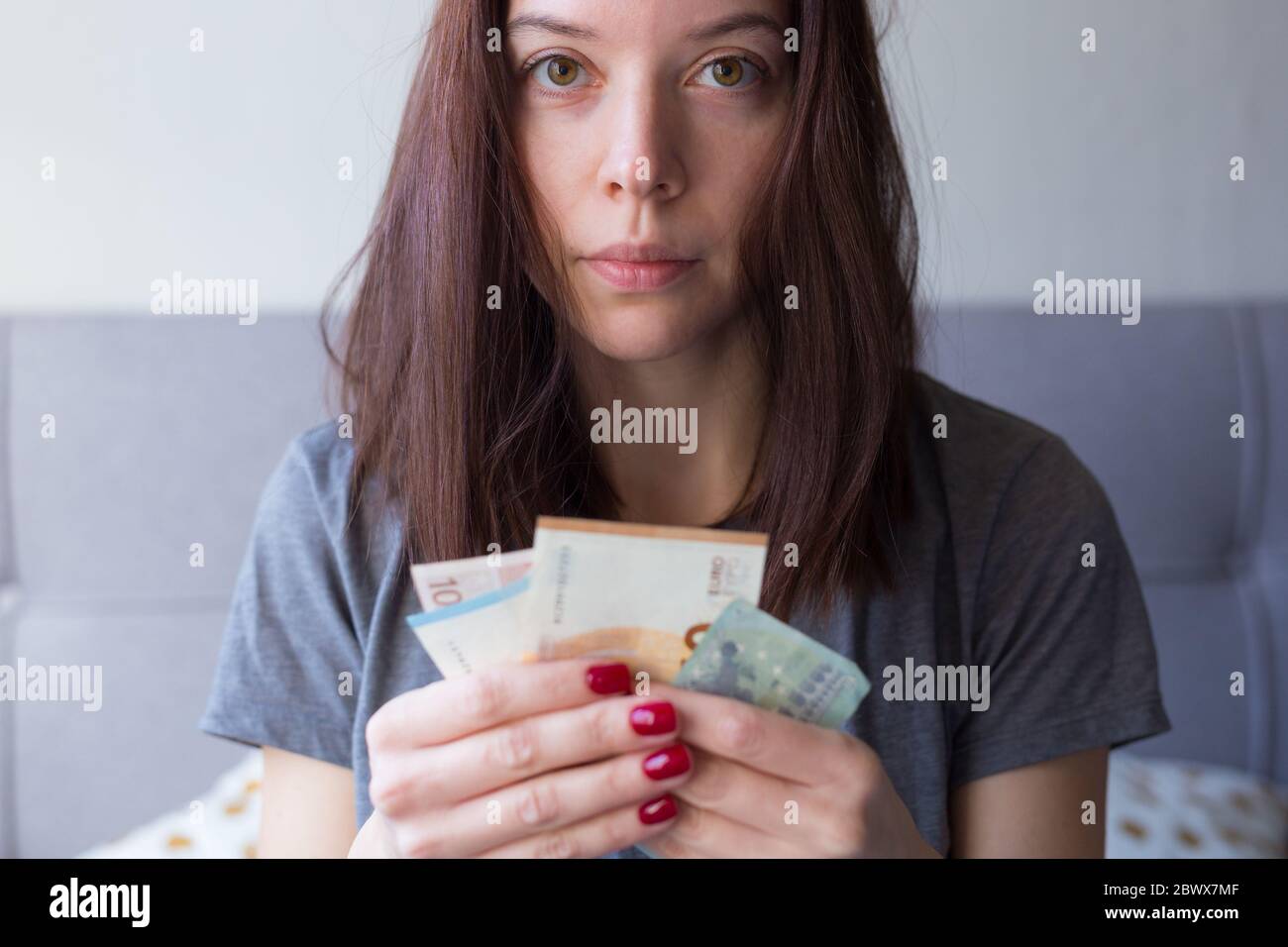 Young sad woman holding euro money in her hands. Economy and financial crisis. Saved money. Financial turmoil crisis. Lack of money. Unemployment Stock Photo