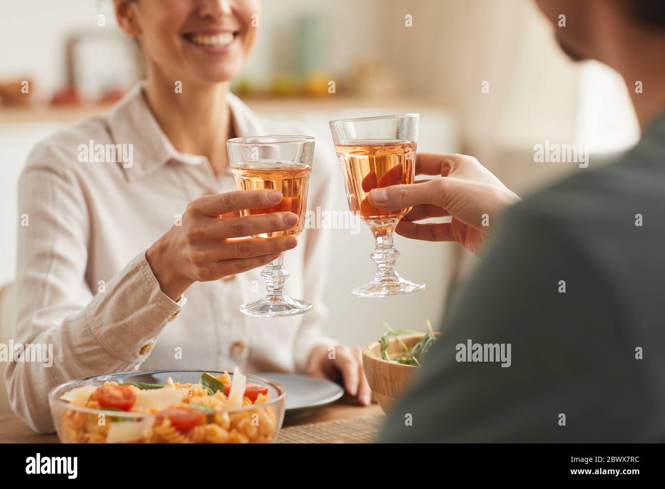 Close-up of young couple having dinner together at the table and toasting with glasses of wine Stock Photo