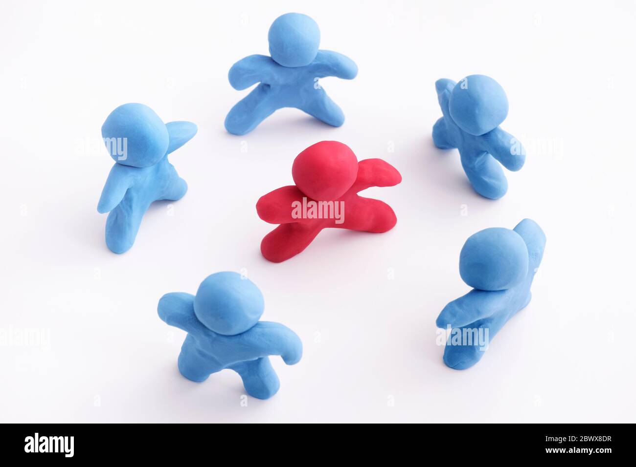 Blue plasticine people surrounding red plasticine person. Stand out from the crowd. Bullying concept. Close up. Stock Photo
