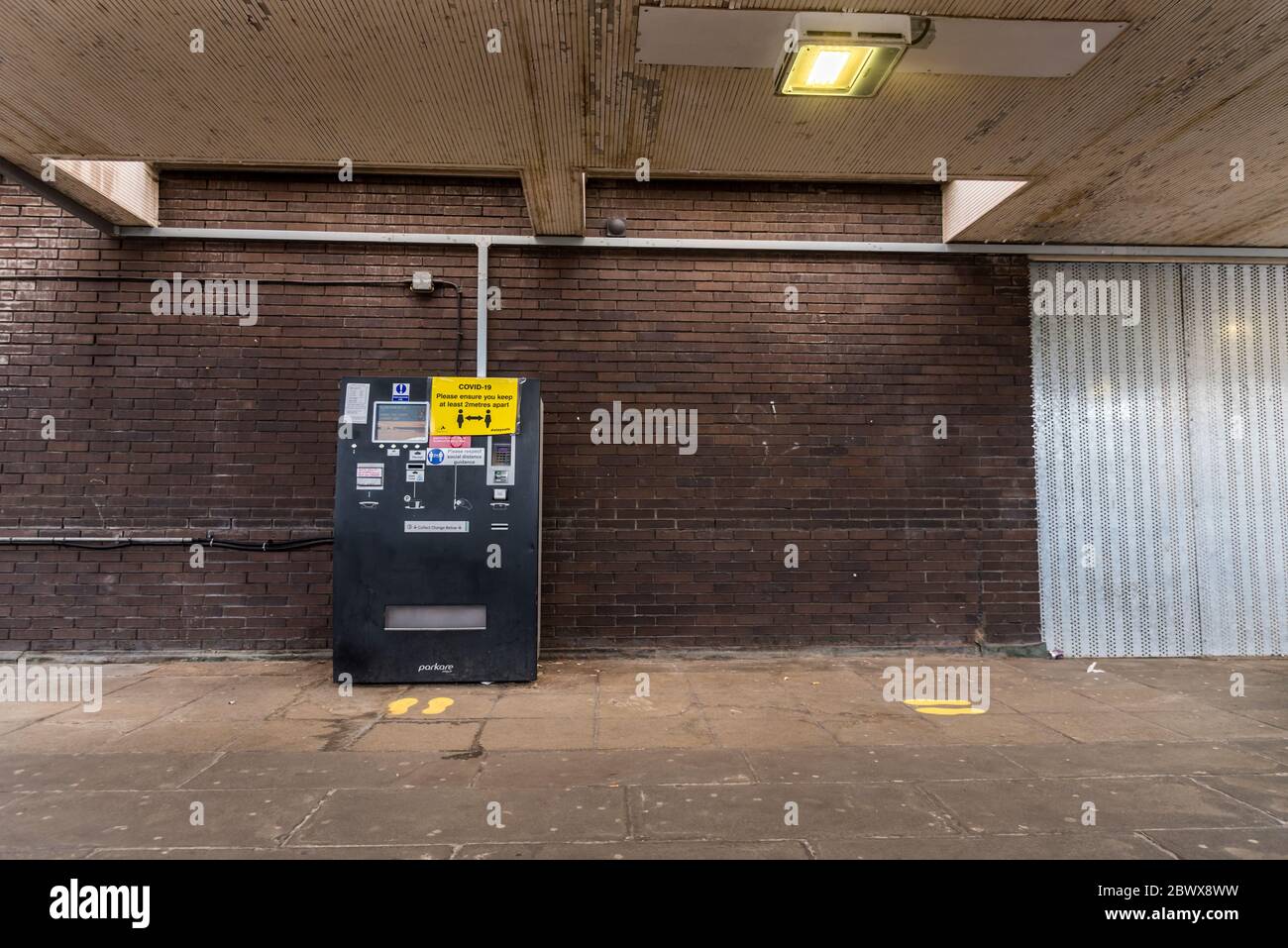 Coventry City/ United Kingdom- 3 June 2020: parking payment machine with social distancing warning reminder. Payment machine with yellow foot marking Stock Photo