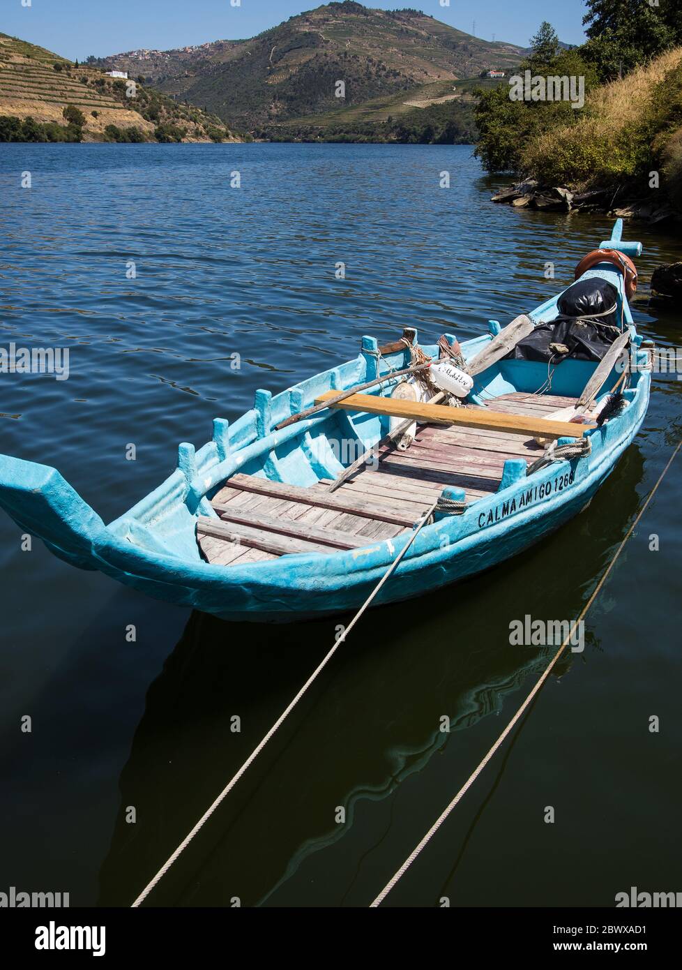 Small open wooden pale blue painted traditional rabelo boat moored along the river Douro Northern Portugal Stock Photo