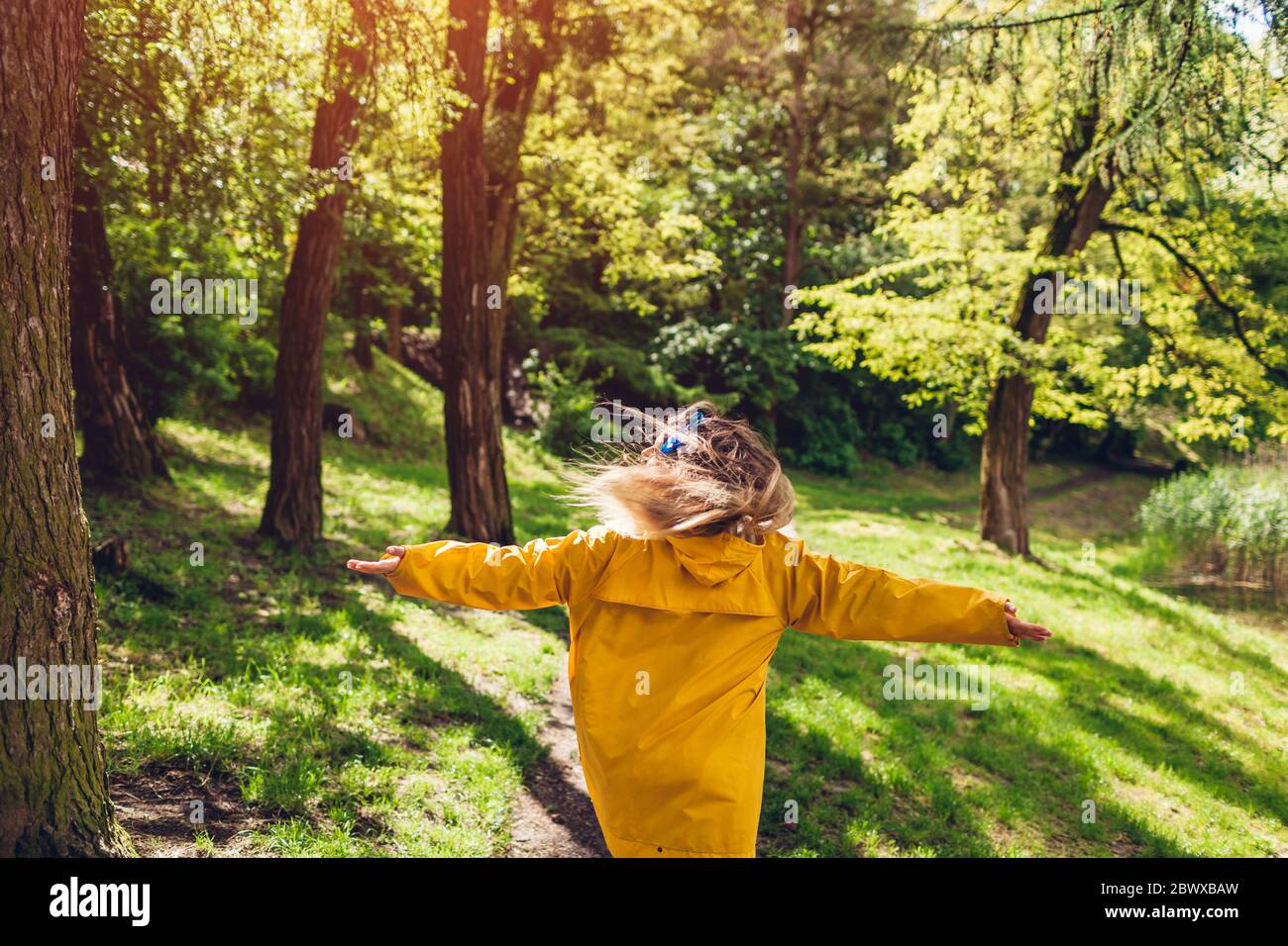 Happy woman in yellow raincoat running jumping feeling free walking in