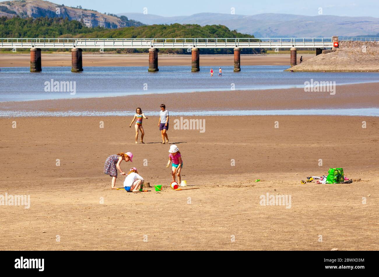 Young children playing and building sand castles  with bucket spade on the beach at the Cumbria seaside holiday resort of Arnside Morecambe Bay Stock Photo