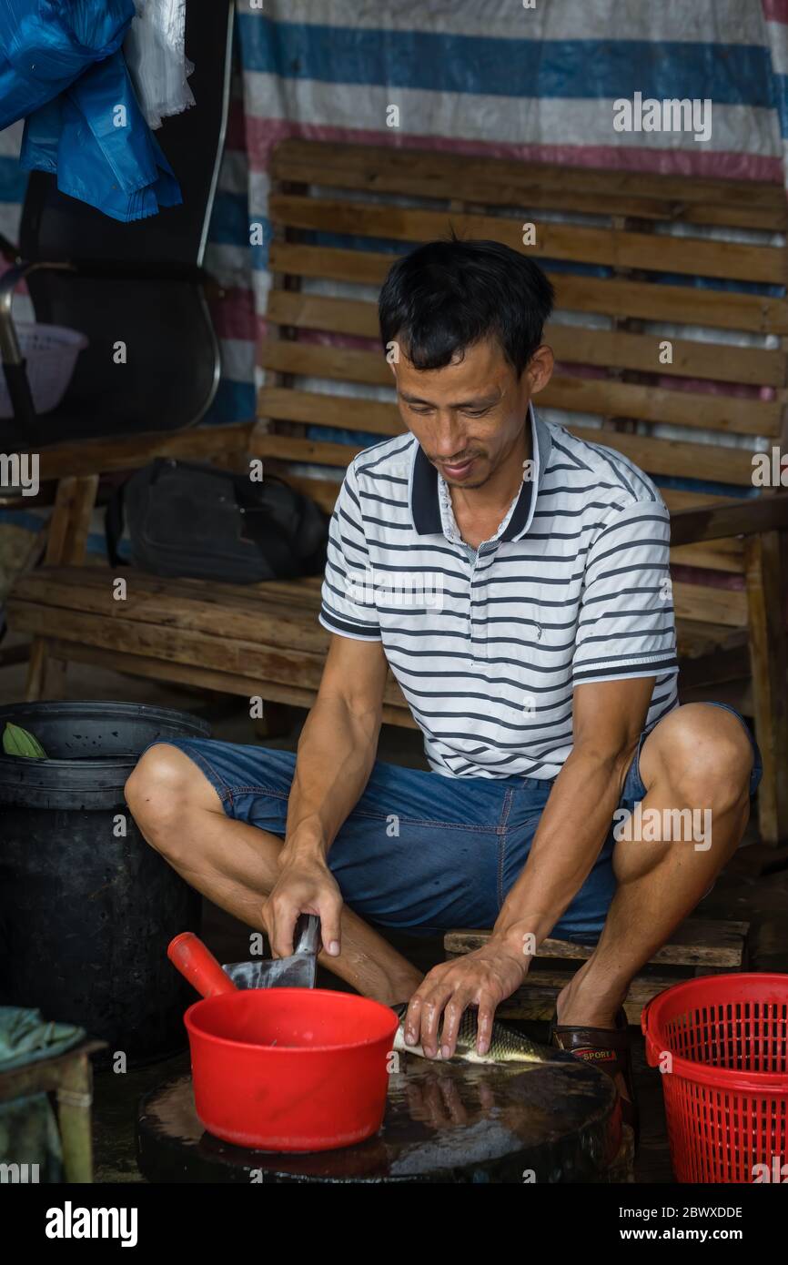 Yangshuo, China August 2019 Chinese worker peeling scales off small