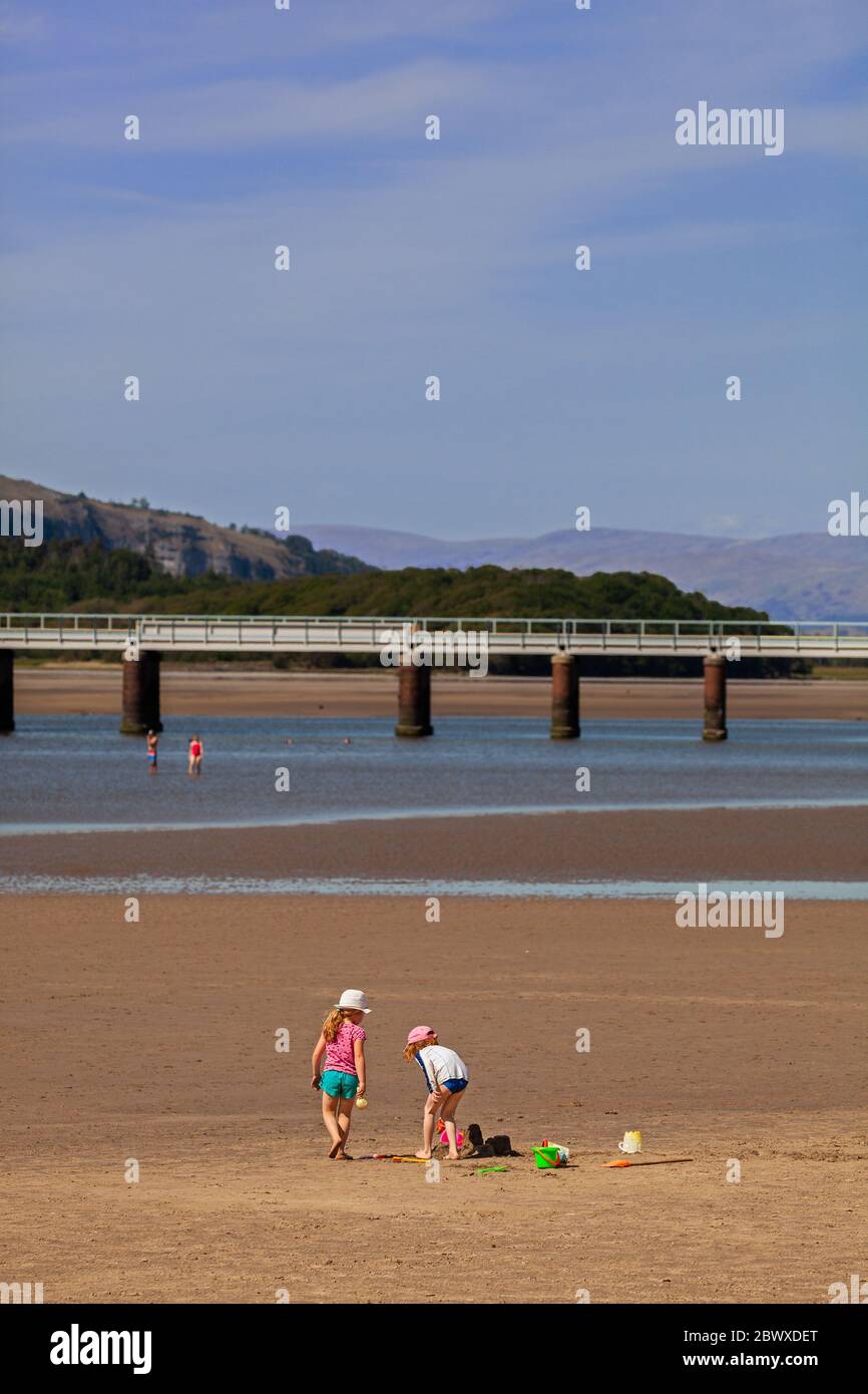 Young children playing and building sand castles  with bucket spade on the beach at the Cumbria holiday resort of Arnside Morecambe Bay Stock Photo