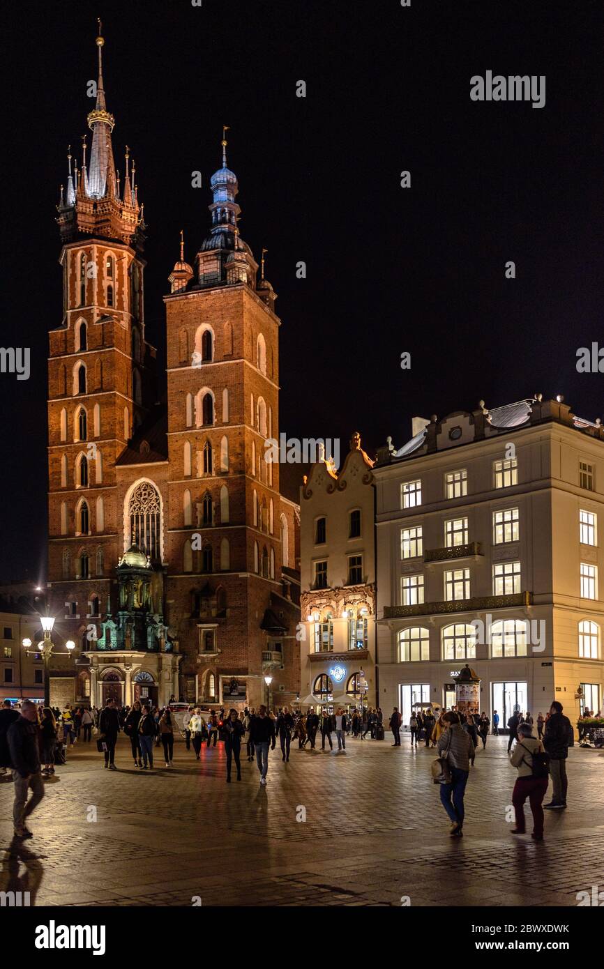 St. Mary's Basilica in Krakow in the Rynek Glowny main square in the old town at night with tourists Stock Photo