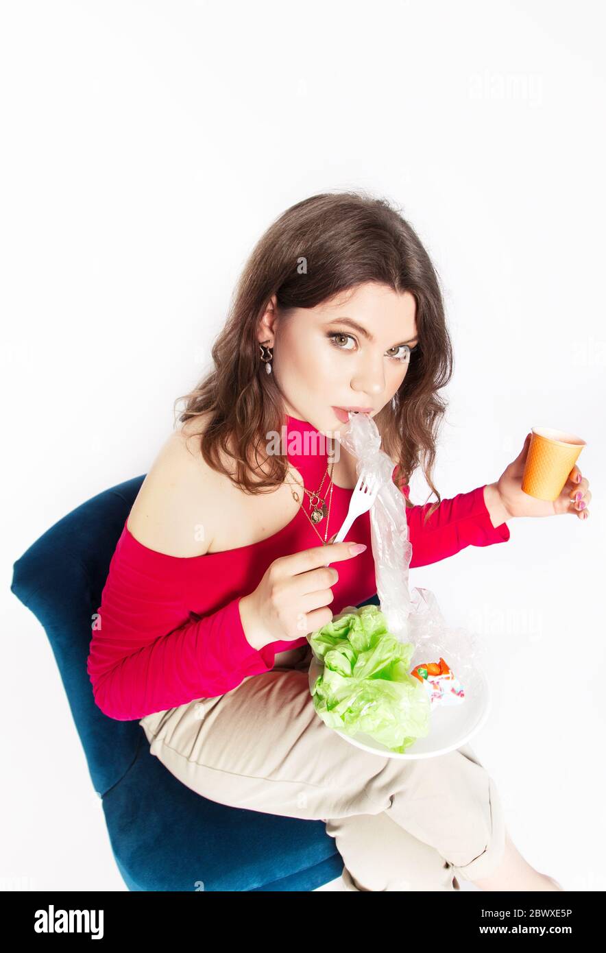 Young beautiful woman eating a plastic bag as a concept of plastic