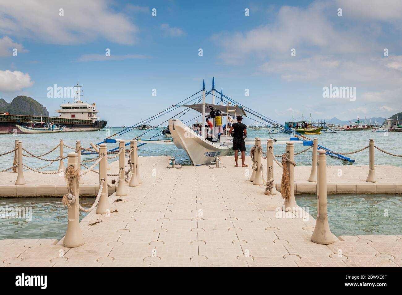 Tourists board the traditional long tail boats in El Nido to head out to the islands and beaches for the day. El Nido, Palawan, The Philippines. Stock Photo