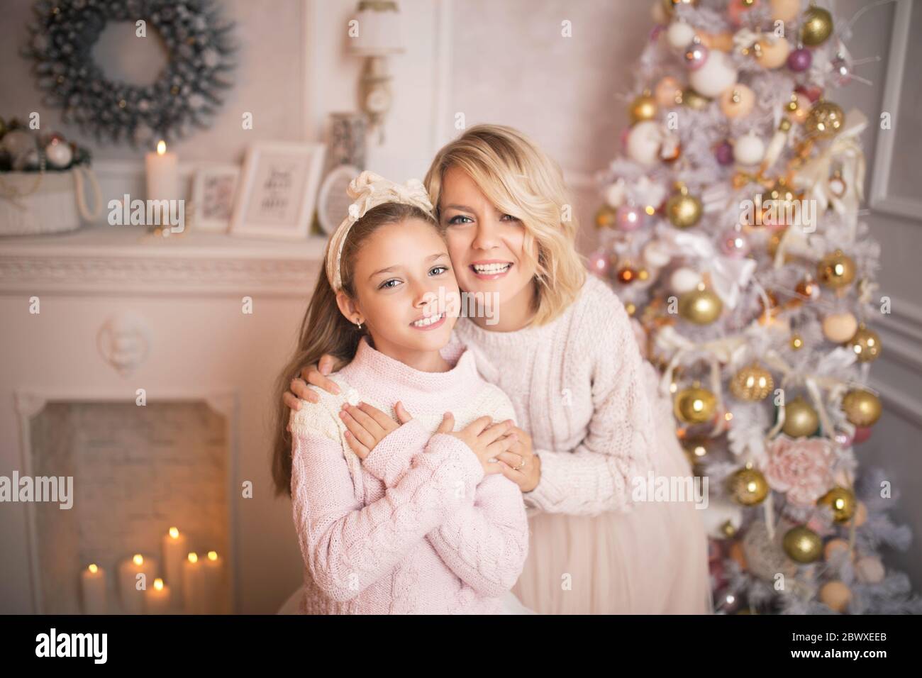 Portrait of a joyful mom and daughter against the background of the Christmas interior. Stock Photo