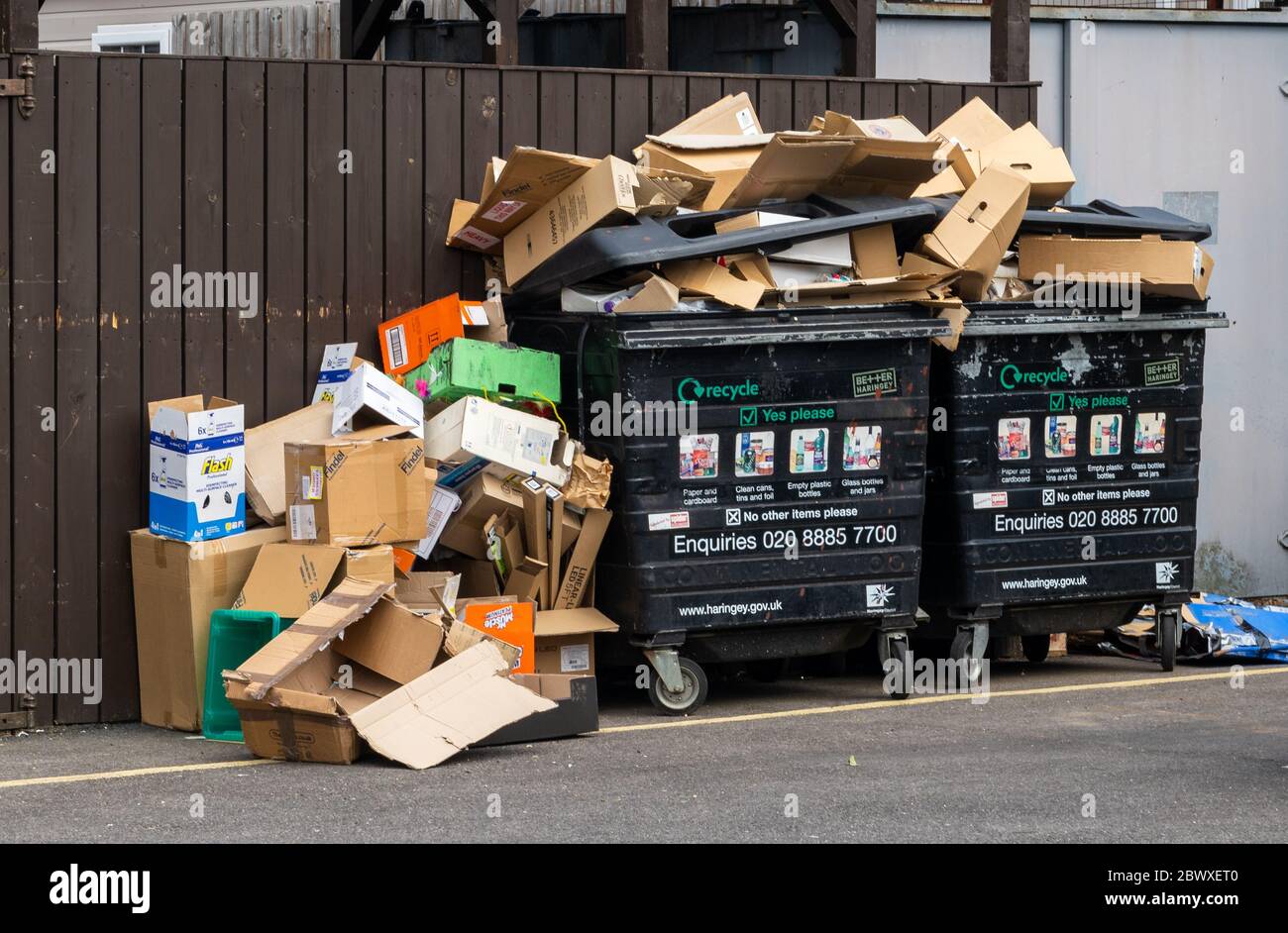 Two commercial recycle bins overflowing with cardboard waste with