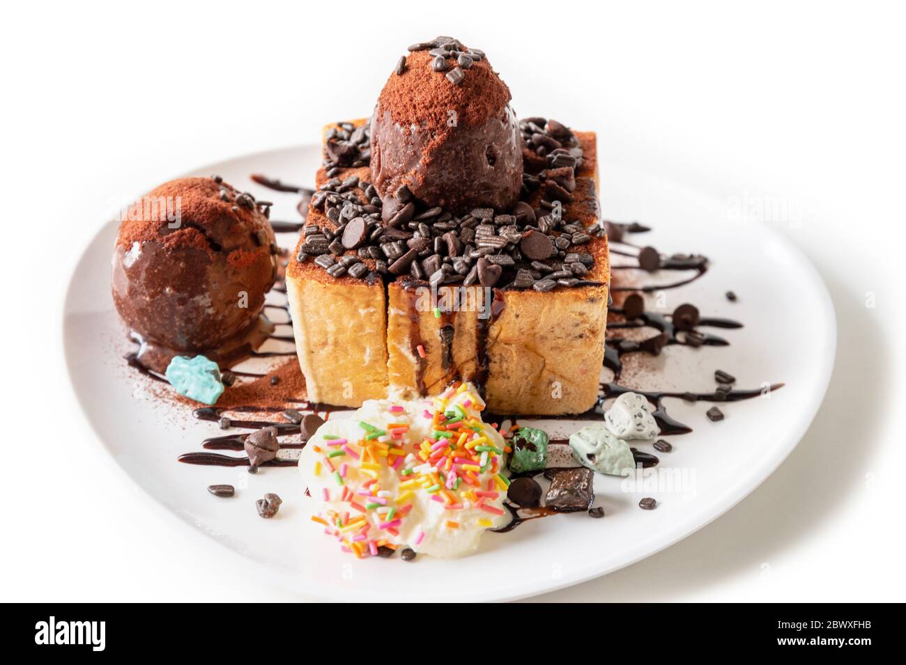 Closeup side view Honey Toast bread and Chocolate brown Ice cream scoop topped with syrup decorate with a chocolate tablet in a white plate on the tab Stock Photo