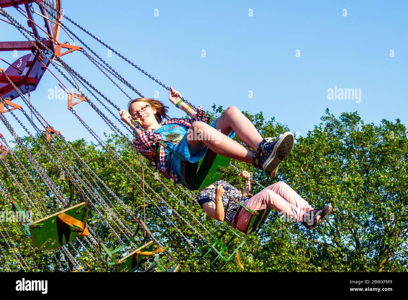 A thirteen year-old girl riding on the swing chairs at a tradition steam fair, London, UK Stock Photo