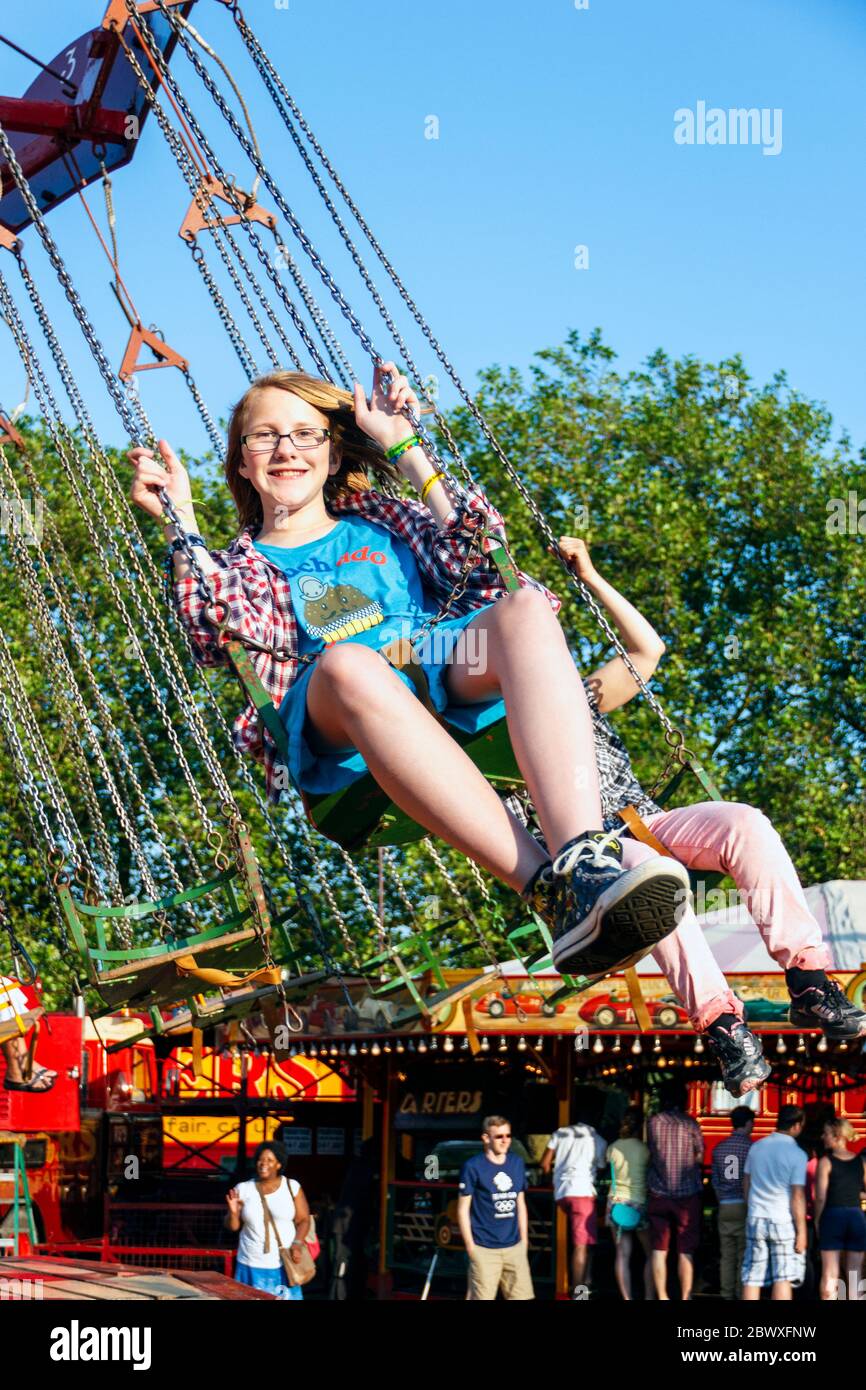 A thirteen year-old girl riding on the swing chairs at a tradition steam fair, London, UK Stock Photo