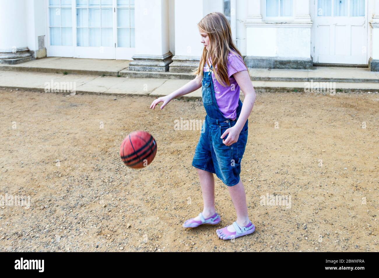 An eleven year-old girl bouncing a basketball in the park, London, UK Stock Photo