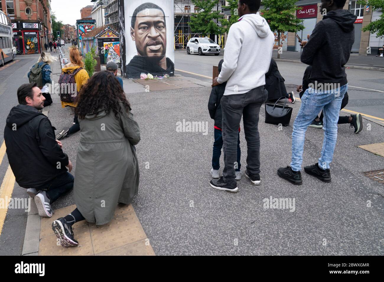 Manchester, UK. 3rd June, 2020. Members of the public some taking the knee are seen by a mural of George Floyd the 46-year-old black man who died in Minneapolis, Minnesota on May 25th after Derek Chauvin, a white officer with the Minneapolis Police Department, pressed his knee to Floyd's neck, Manchester, UK. Credit: Jon Super/Alamy Live News. Stock Photo