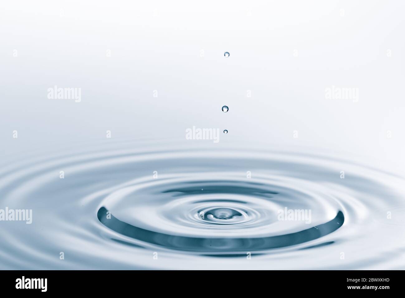 Waves on the surface of the water from a collision. Drop of water drop to the surface. Stock Photo