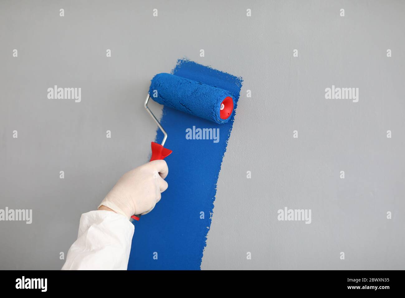 Male painter in uniform paints wall with roller Stock Photo Alamy