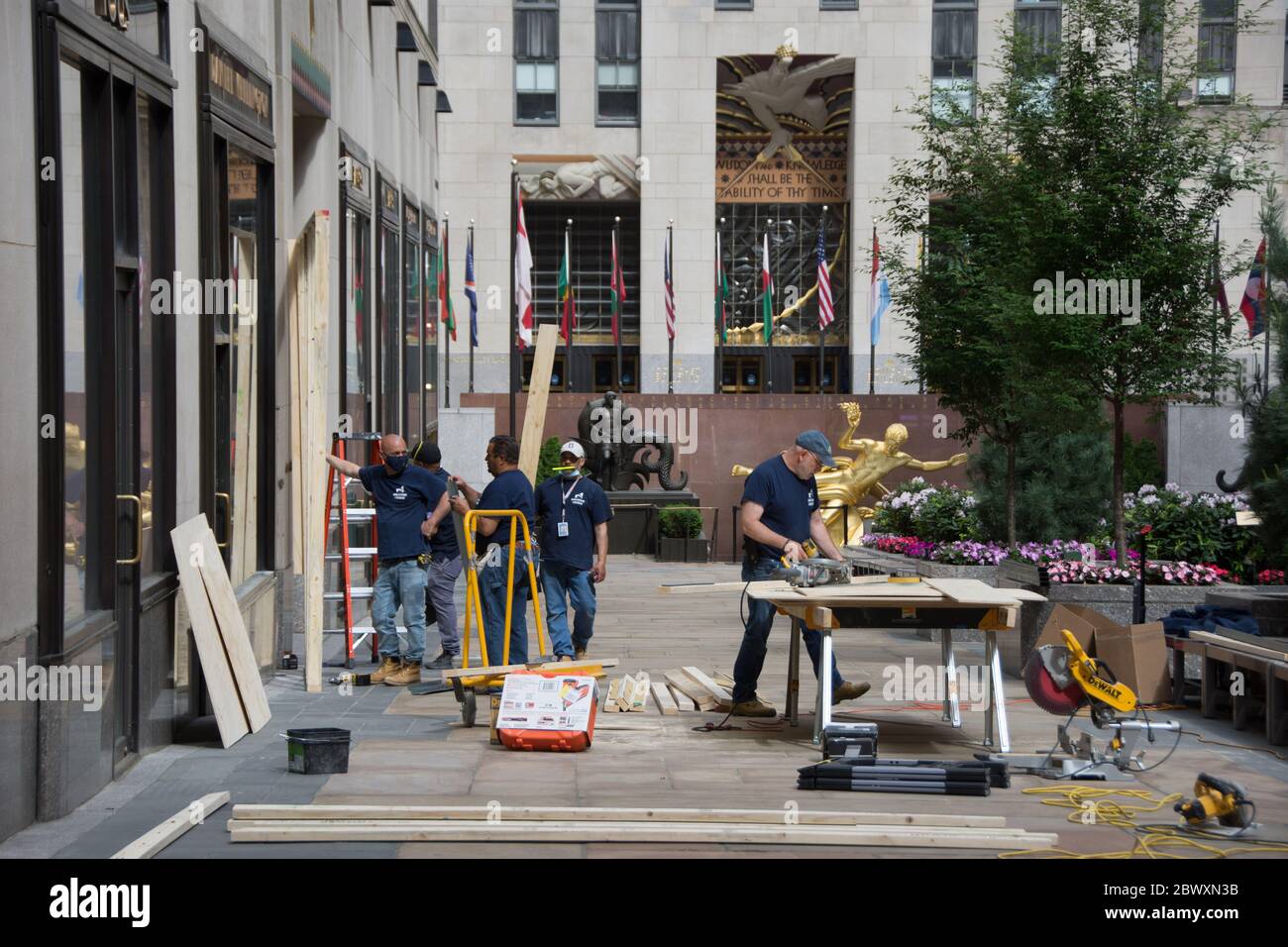Workers installing plywood protections on store windows in the Channel Garden at Rockefeller Center. Stock Photo
