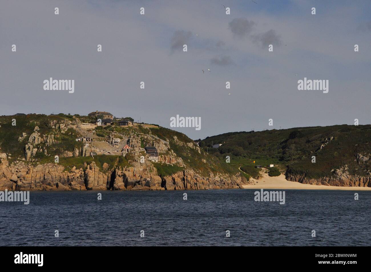 Minack theatre on the cliff face taken from the sea, Porthcurno in Cornwall.UK. On right is the Porthcurno beach where the major undersea telephone ca Stock Photo