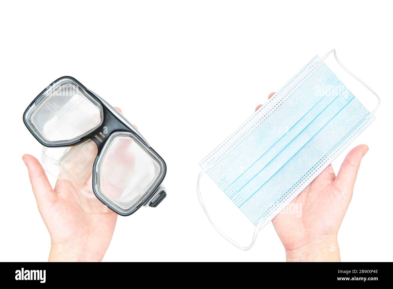 Top view of female hands holding a medical face mask and a scuba mask against a white background. Options for summer vacation 2020. Coronavirus impact Stock Photo