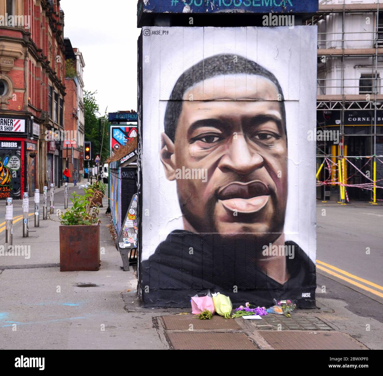 Flowers have been left at a mural depicting George Floyd, painted by street artist Akse, which has recently appeared in Stevenson Square, central Manchester, England, United Kingdom. Floyd, an African-American man, died in Minneapolis, Minnesota, United States, on May 25, 2020, while being arrested by 4 police officers after a shop assistant alleged he tried to pay with a counterfeit $20 bill. Stock Photo
