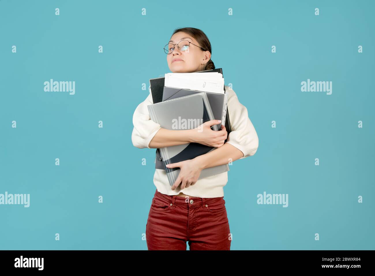 Girl hugs a large stack of documents and folders. Overloaded office employee Stock Photo