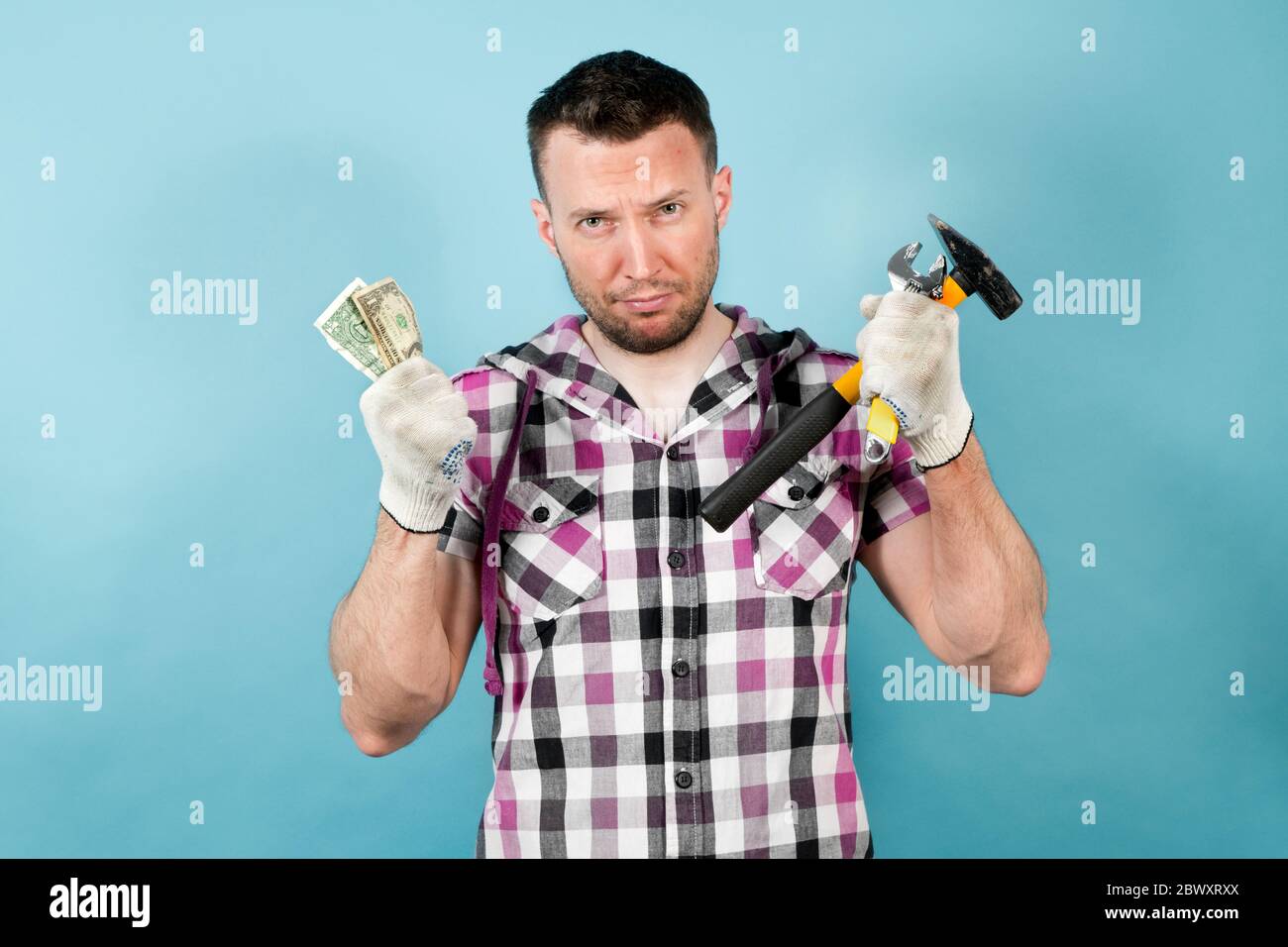 a dirty hard worker holds tools in one hand and several crumpled dollars in  the other. He worked hard, got dirty and tired, but received very little f  Stock Photo - Alamy, image size:1300x956