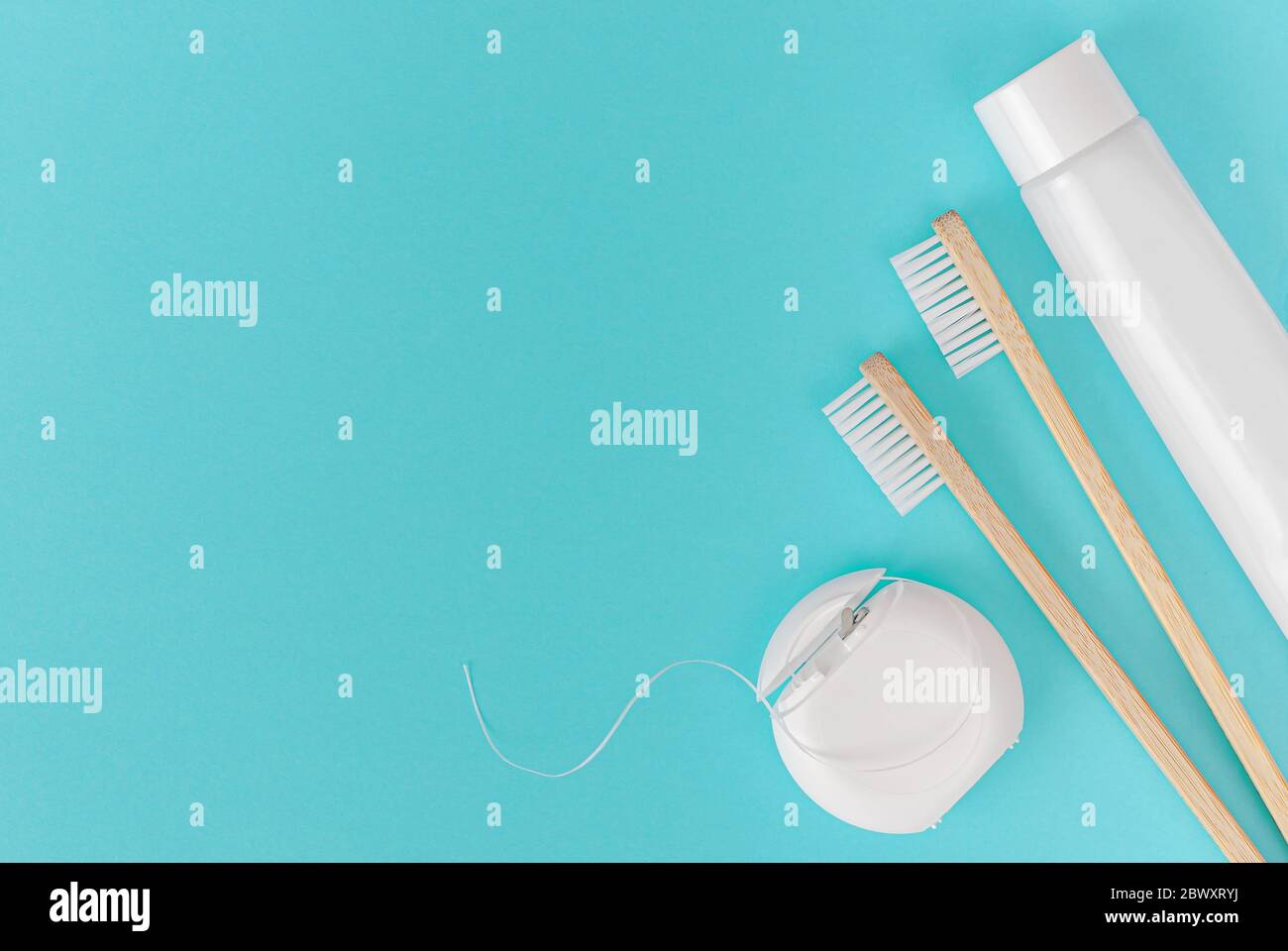 Bamboo toothbrush, toothpaste tube and dental floss on blue background. Dental care, overhead Stock Photo
