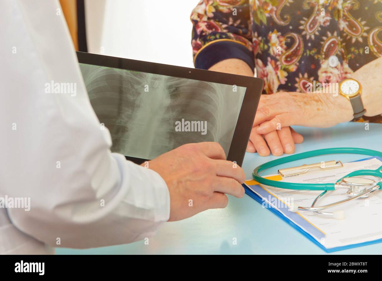 Doctor shows elderly woman MRI results on tablet screen Stock Photo