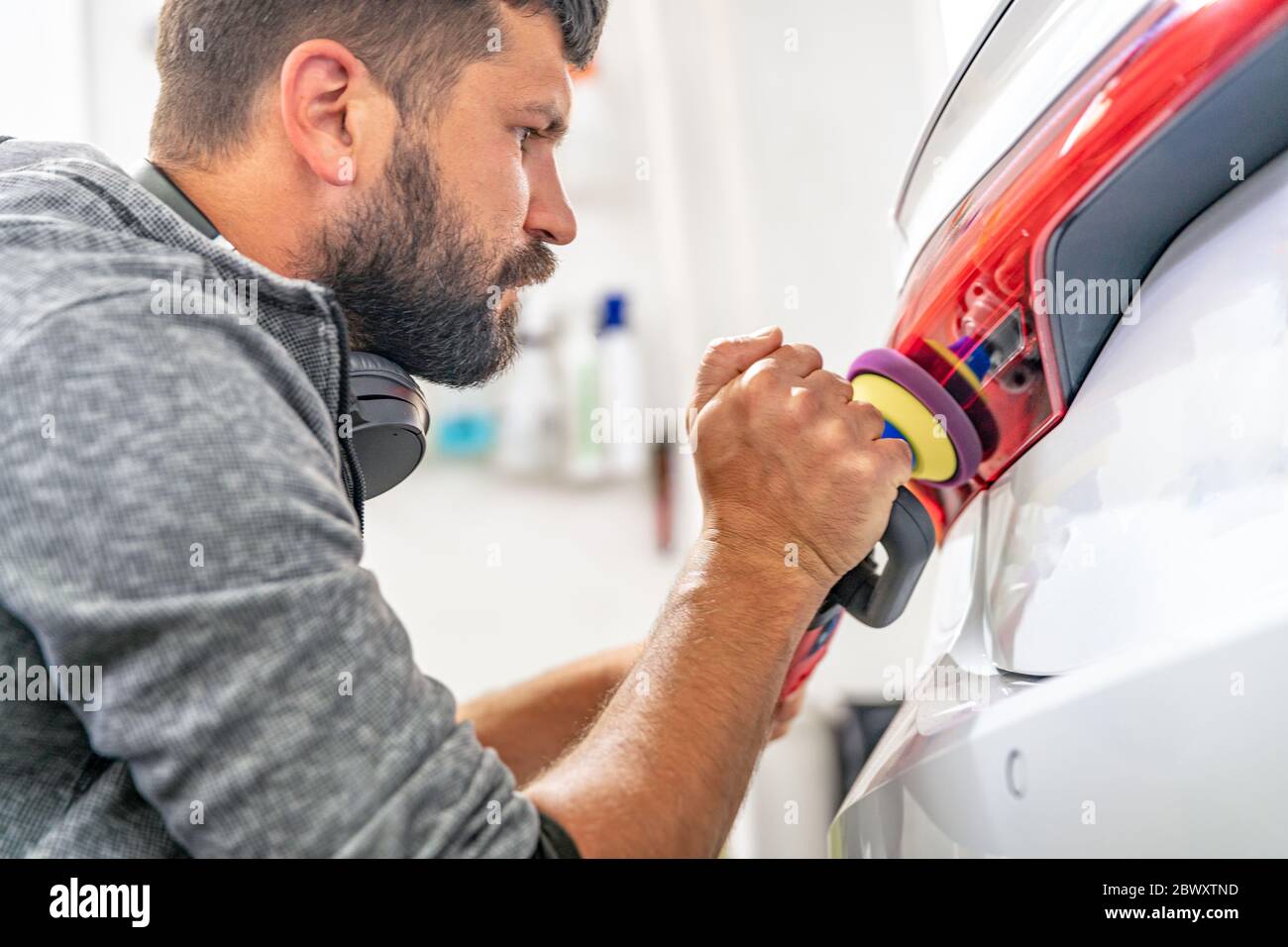 manual polishing of the headlight of luxury cars with the application of protective equipment Stock Photo