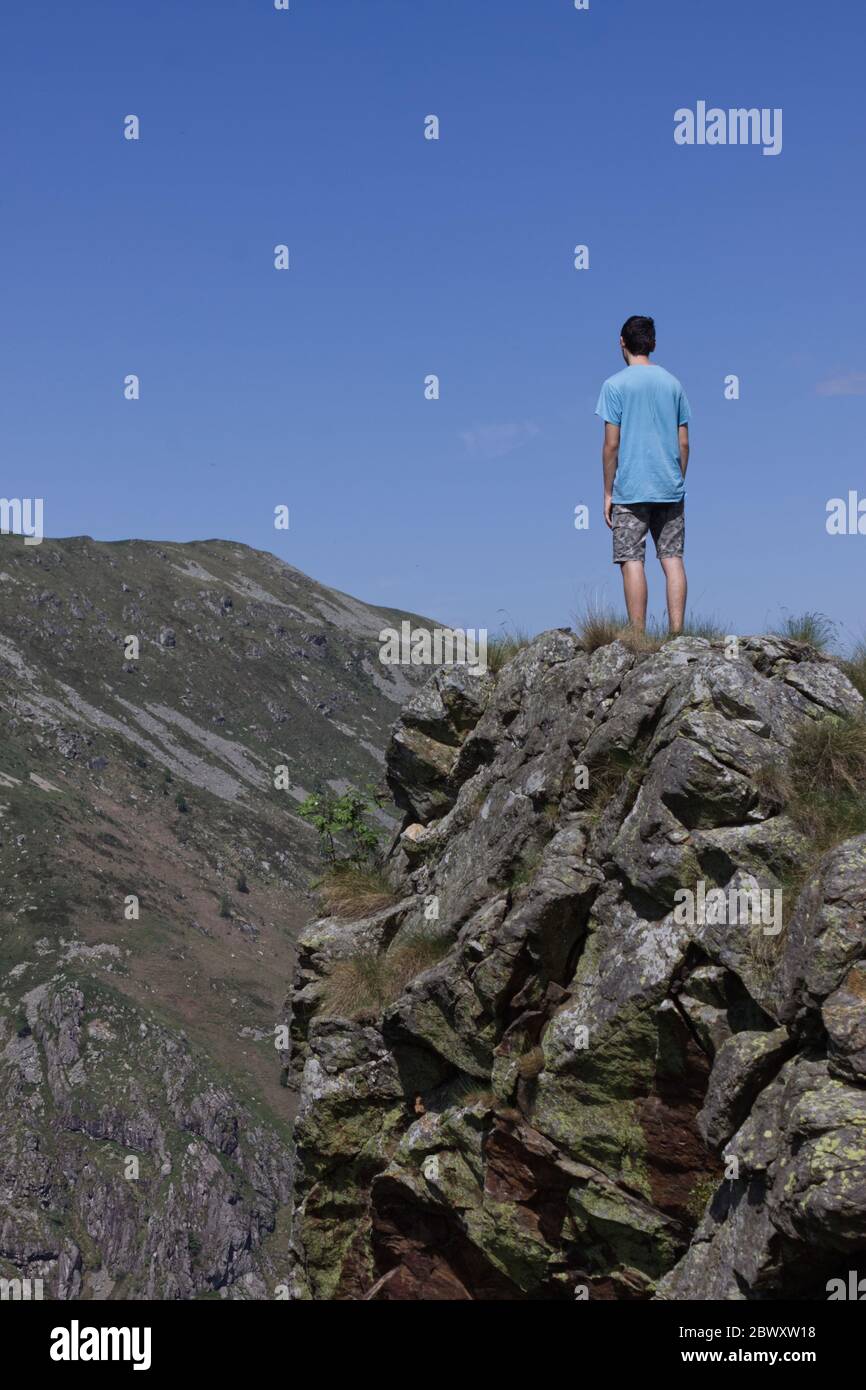 A boy standing on a spur of rock observes a panorama of morenic hills ...