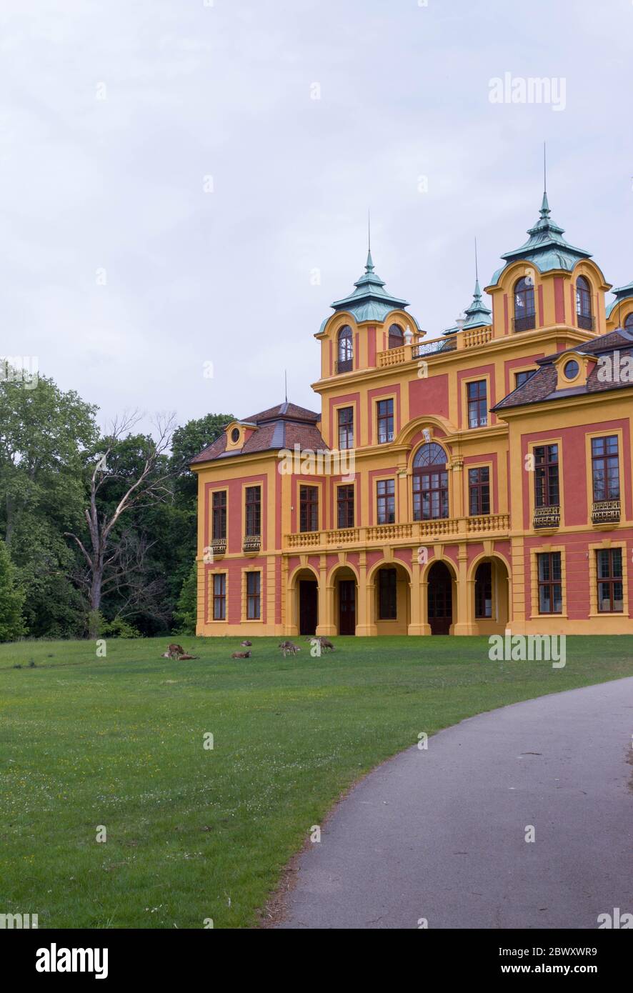 18th century red and yellow fairytale castle 'Schloss Favorite' in Ludwigsburg, Germany with deer on green lawn Stock Photo