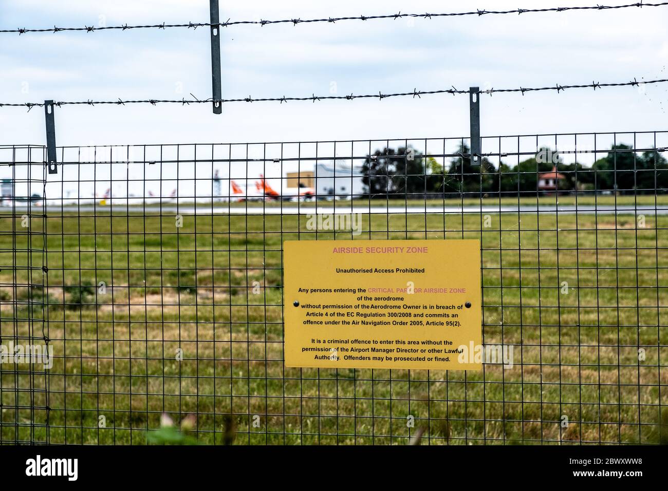 Warning of trespass on London Southend Airport outskirts fence advising on penalty and law to cease entering the airport areas. Stock Photo