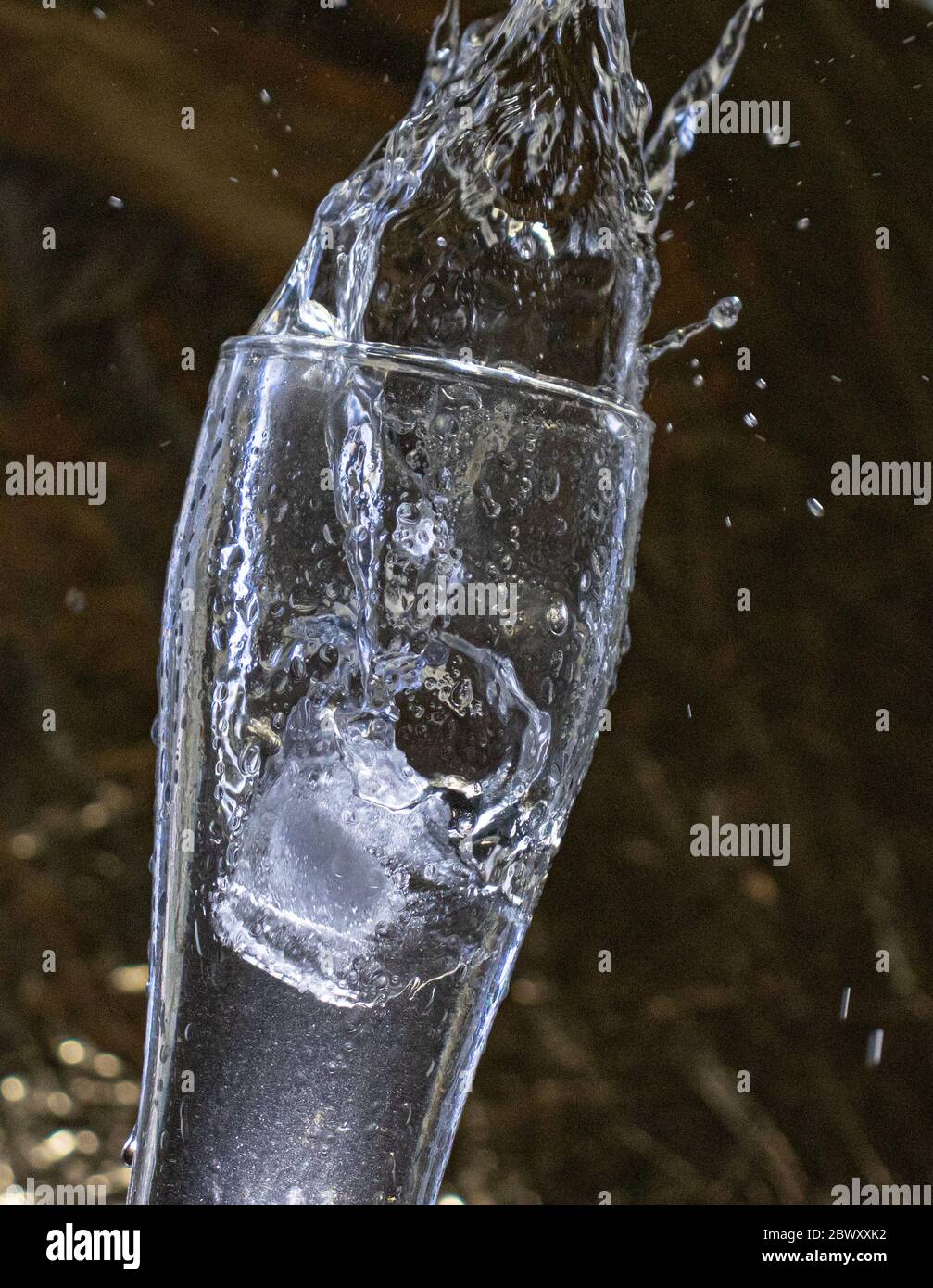 https://c8.alamy.com/comp/2BWXXK2/tall-glass-with-condensation-and-ice-splashing-clear-liquid-on-a-gold-background-2BWXXK2.jpg