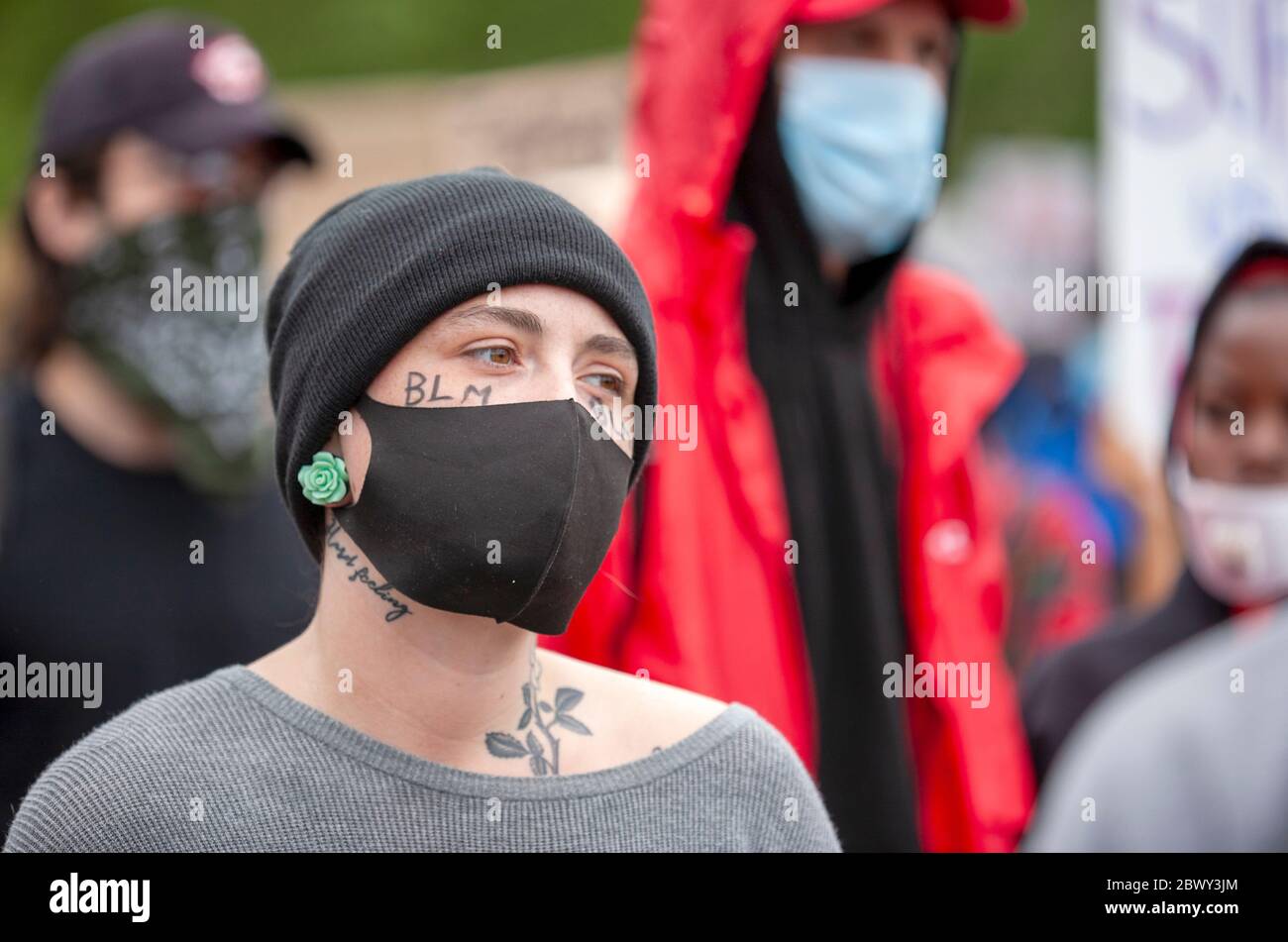 Young woman, with neck tattoos, wearing a black hat and protective face mask during the Black Lives Matter UK protest march. London, England, UK Stock Photo