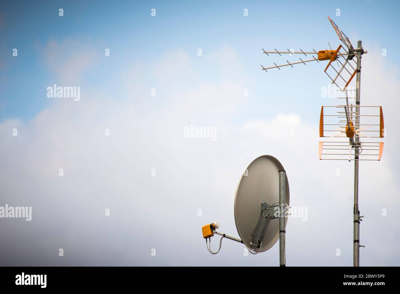TV aerial and parabolic dish with blue sky background. Wallpaper with