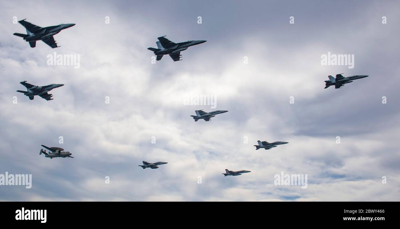 U.S. Navy Aircraft from Nimitz Carrier Strike Group fly in formation over the aircraft carrier USS Nimitz underway conducting composite training unit exercise June 2, 2020 in the Pacific Ocean. Stock Photo