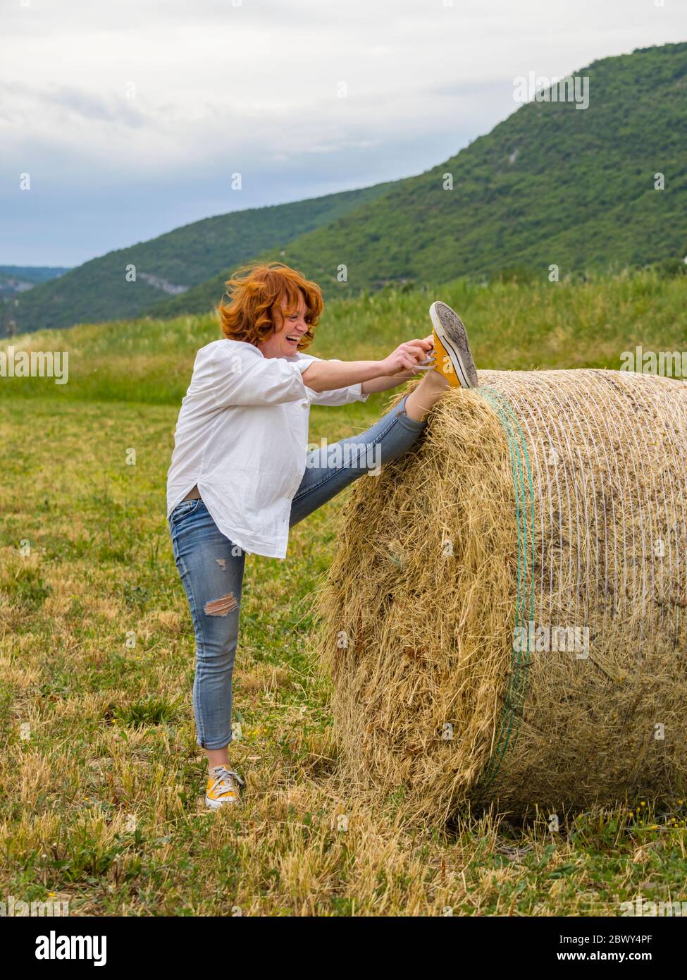 Mature woman on hay haystack in field Stock Photo