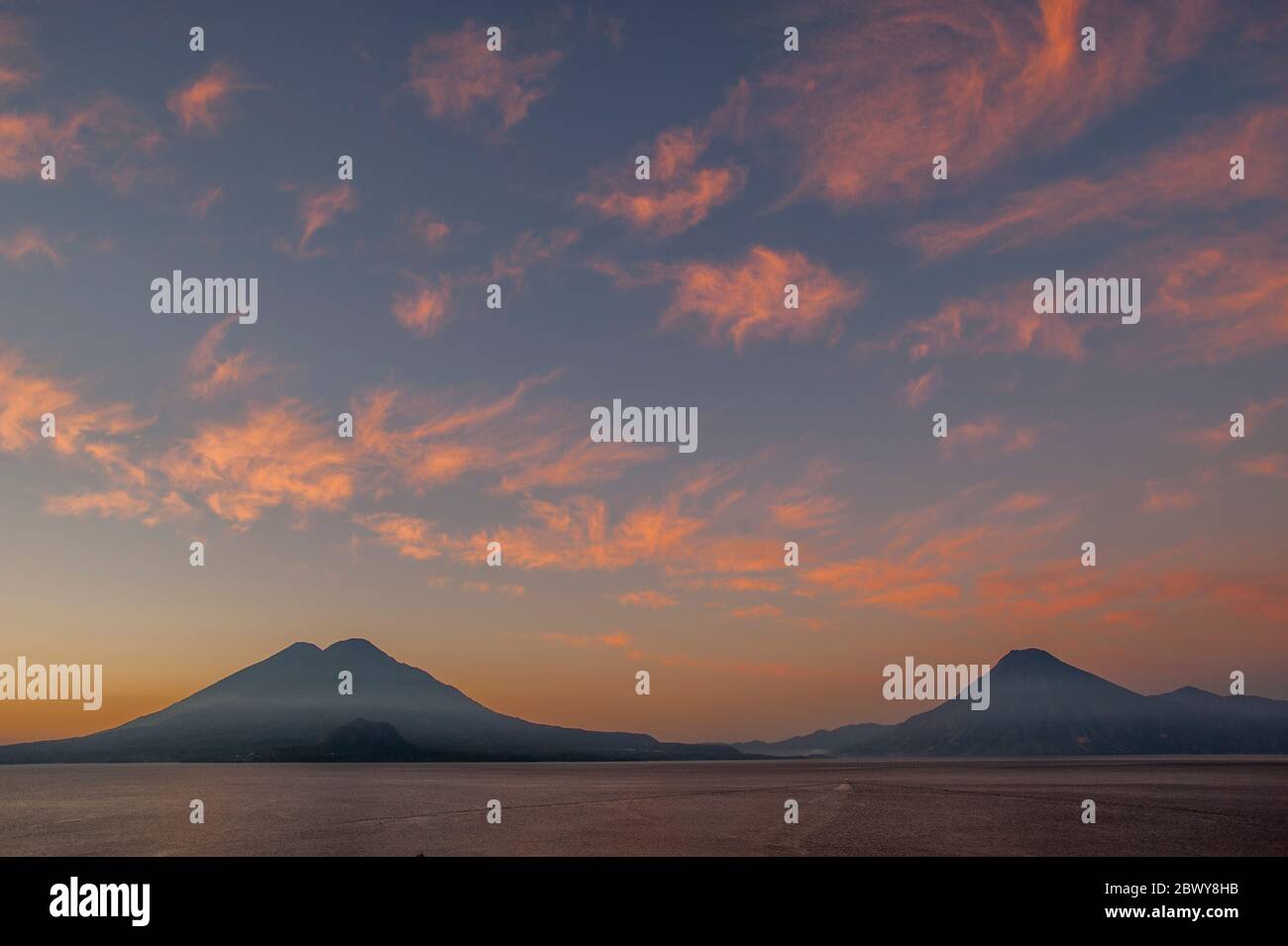 Sunrise over Lake Atitlan with Toliman and Atitlan Volcanoes (left) and San Pedro Volcano (right) in the southwestern Guatemalan Highlands, Guatemala. Stock Photo