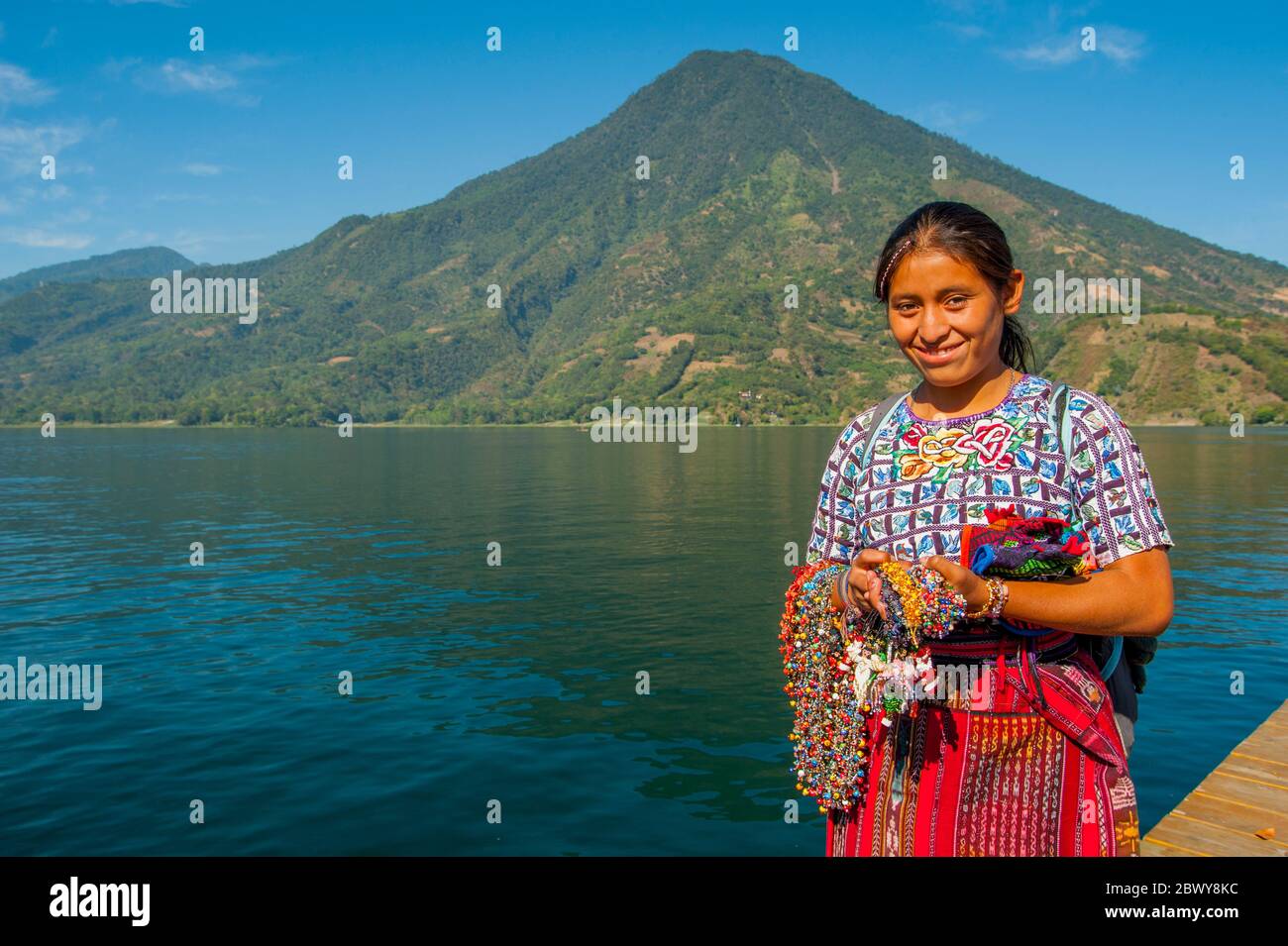 A young Mayan woman at Lake Atitlan with San Pedro Volcano near the town of Santiago in the southwestern highlands of Guatemala. Stock Photo