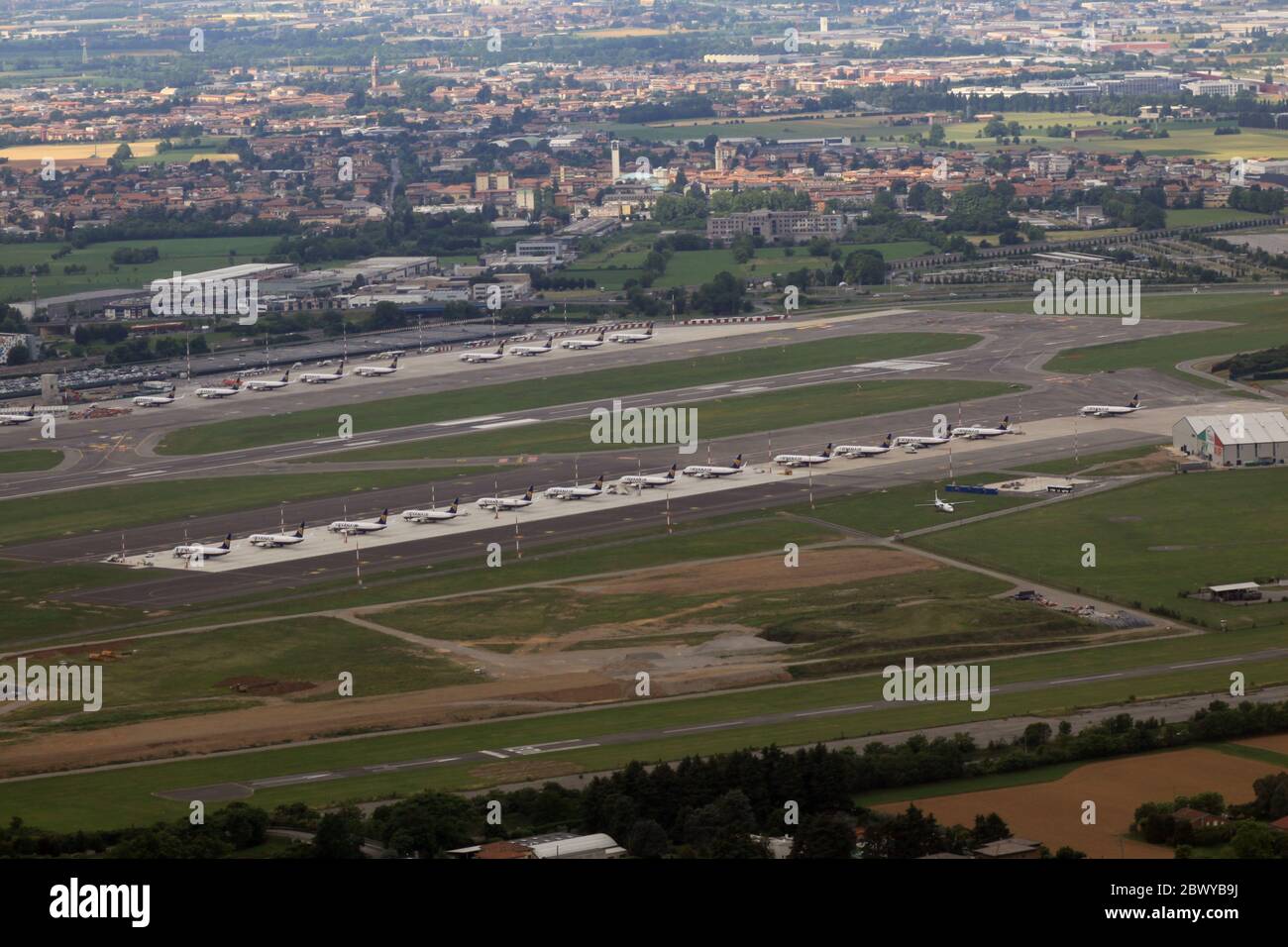 Aerial view of Bergamo airport, which is a Ryanair hub. Dozens of grounded planes line up in Bergamo (LIME/BGY) International Airport due to lockdown measures for coronavirus 2019. The airport itself closed and air traffic is reduced. The planes are flown regularly to keep them airworthy. Stock Photo