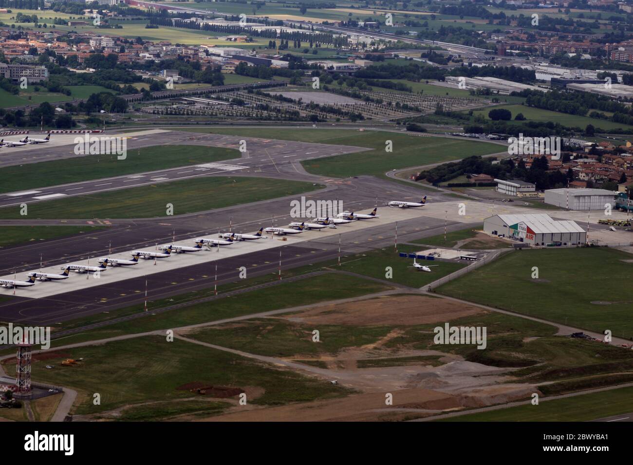 Aerial view of Bergamo airport, which is a Ryanair hub. Dozens of grounded planes line up in Bergamo (LIME/BGY) International Airport due to lockdown measures for coronavirus 2019. The airport itself closed and air traffic is reduced. The planes are flown regularly to keep them airworthy. Stock Photo