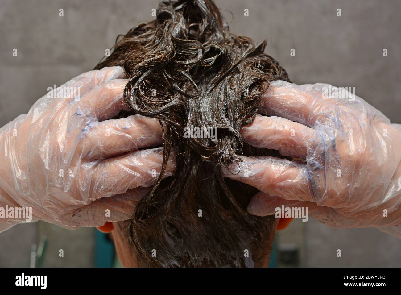 Young woman dyes her hair at home. The girl coloring her hair in her own bathroom. Quarantine, home hair care, stay at home concept. Stock Photo