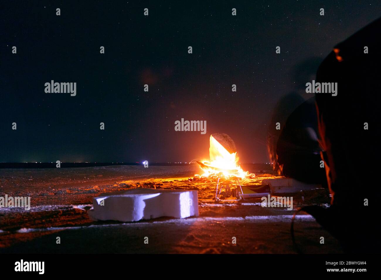 A tent glows under a night sky full of stars at the beach near the cam fire Stock Photo