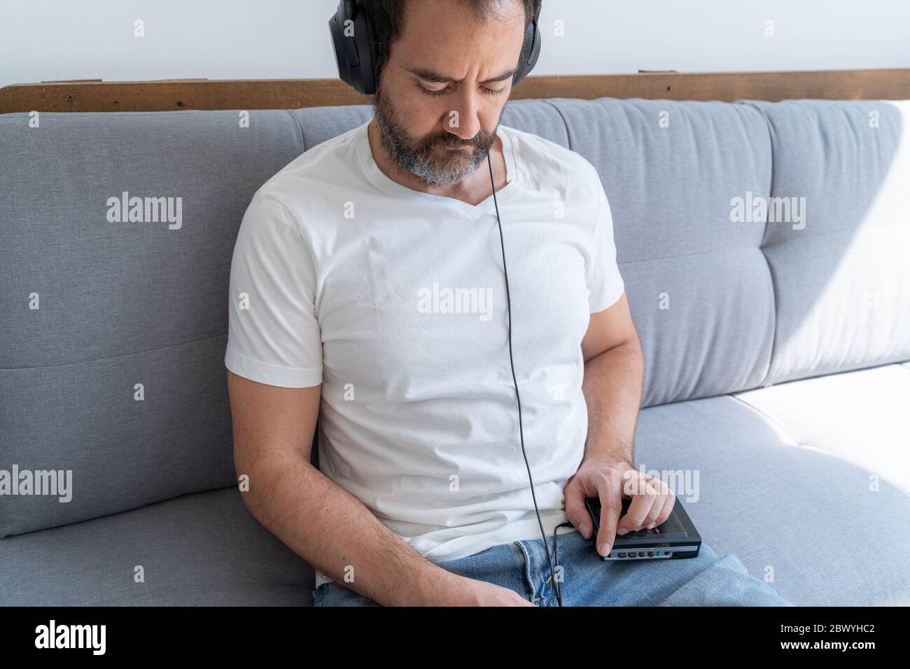 Listening to music with a cassette player on the living room sofa during coronavirus quarantine Stock Photo