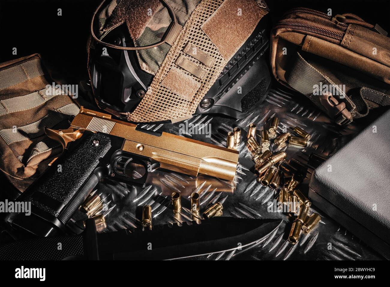 Photo of a tactical helmet, bullet shells, knife and desert eagle gun laying on metal surface. Stock Photo