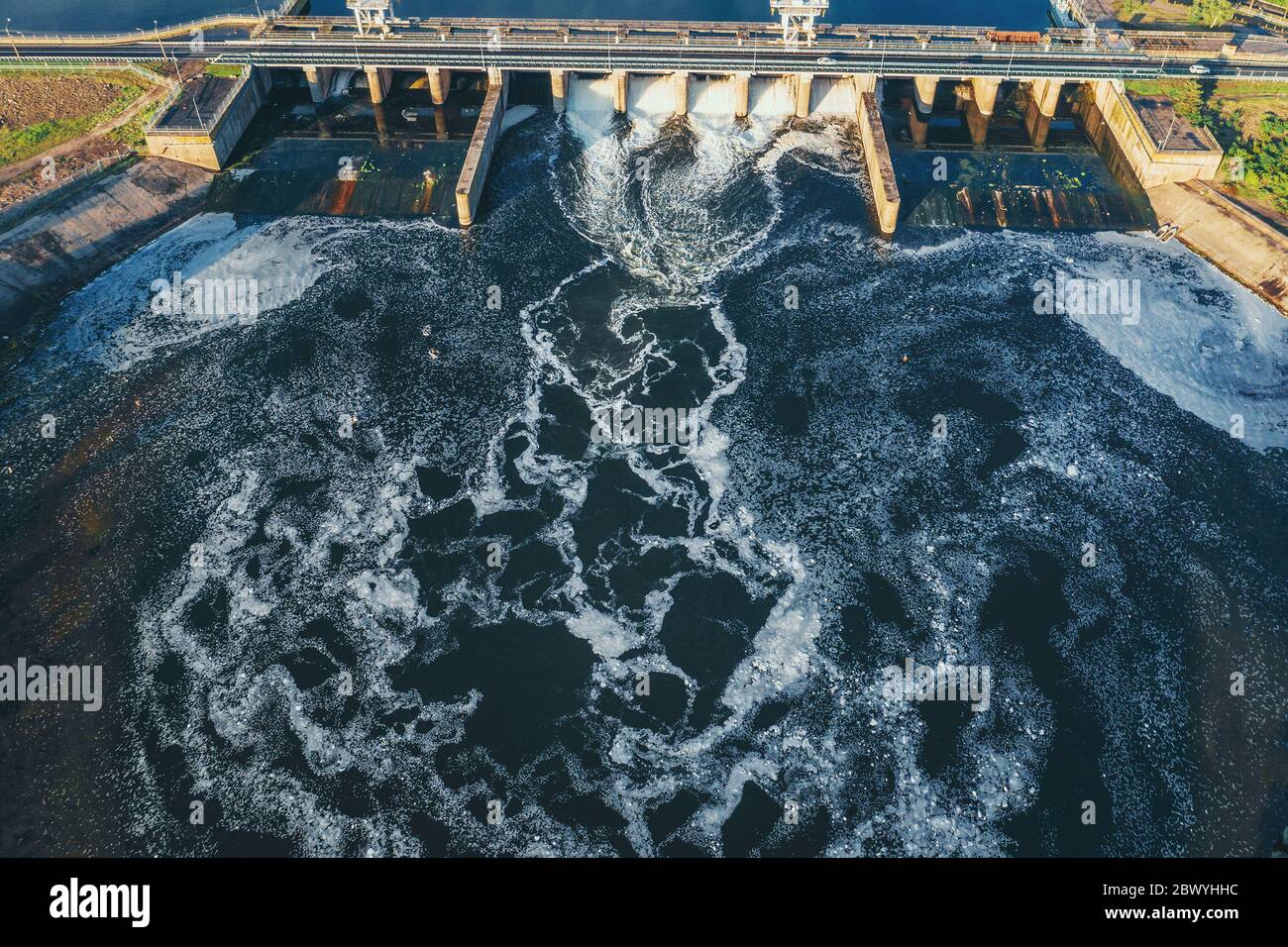 Hydroelectric dam or hydro power station at water reservoir, aerial view from drone. Draining water through gate, hydropower. Stock Photo