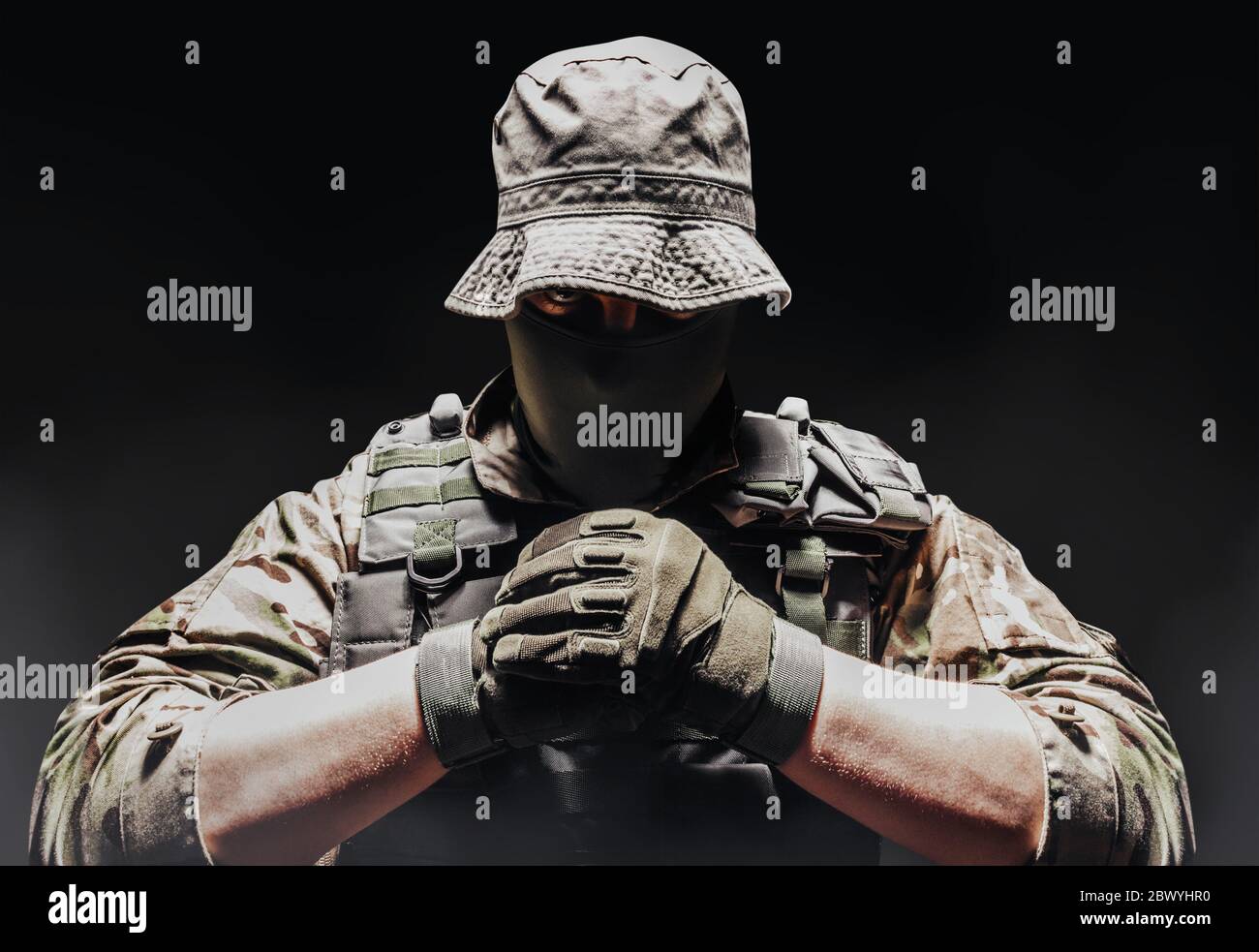 Photo of a fully equipped camouflaged soldier in panama hat posing with