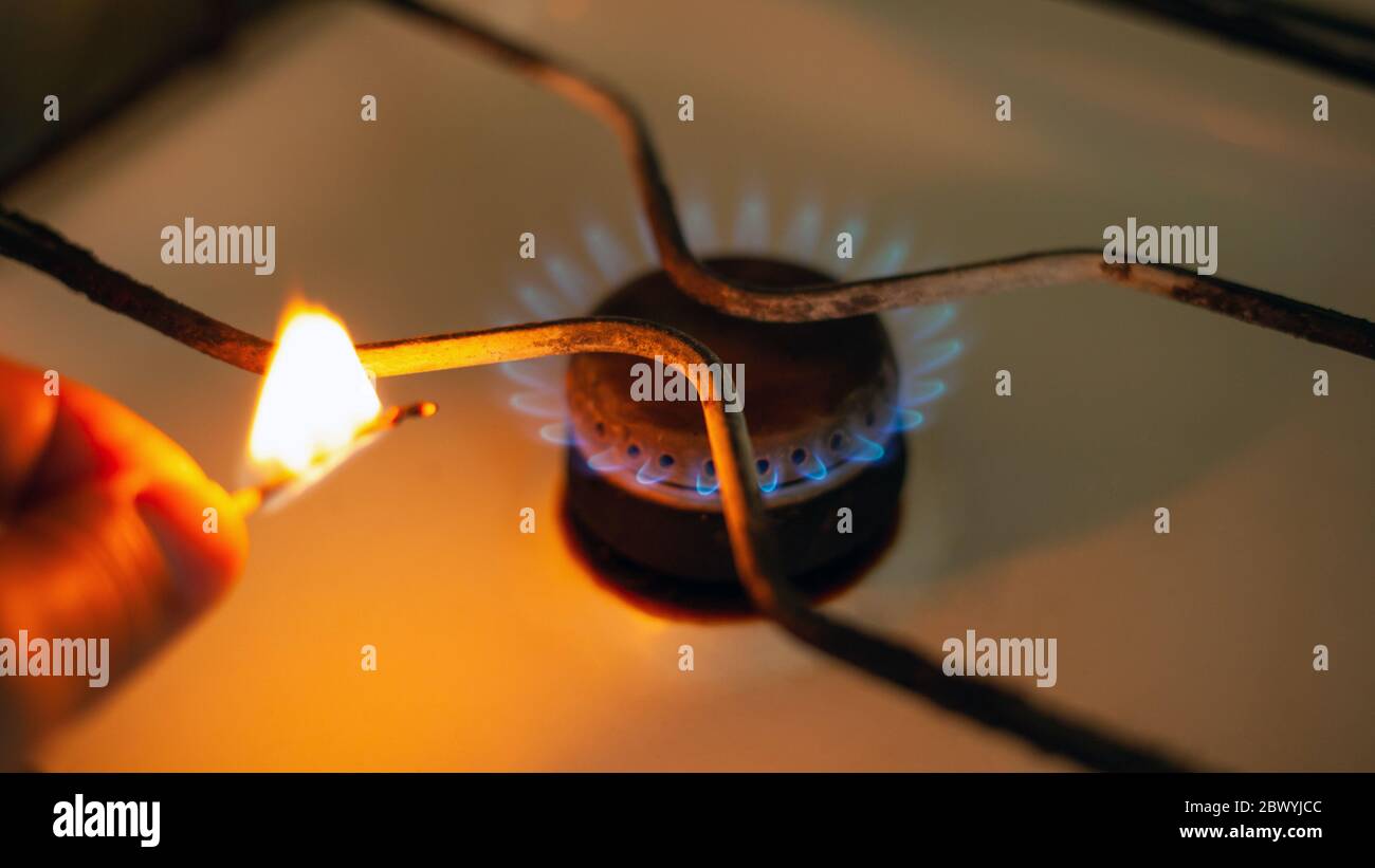 man lights a gas stove with a match closeup. white gas stove with