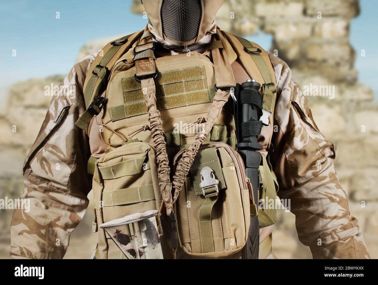 Photo of a fully equipped soldier in uniform, armor, helmet and mask  standing in desert battlefield background close-up view Stock Photo - Alamy